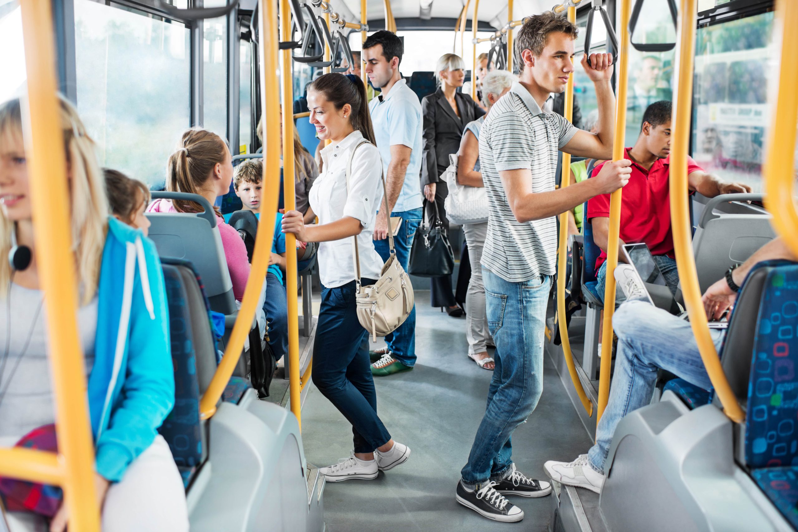 A group of people riding a bus, some standing and some seated.